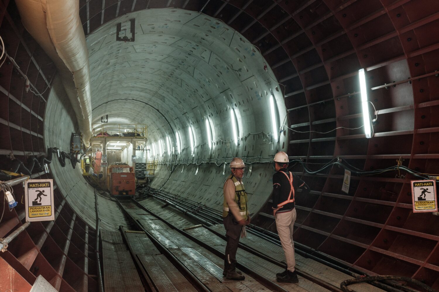 Des ouvriers discutent au bout du chantier de construction du tunnel avec un tunnelier pour la phase 2 du projet MRT