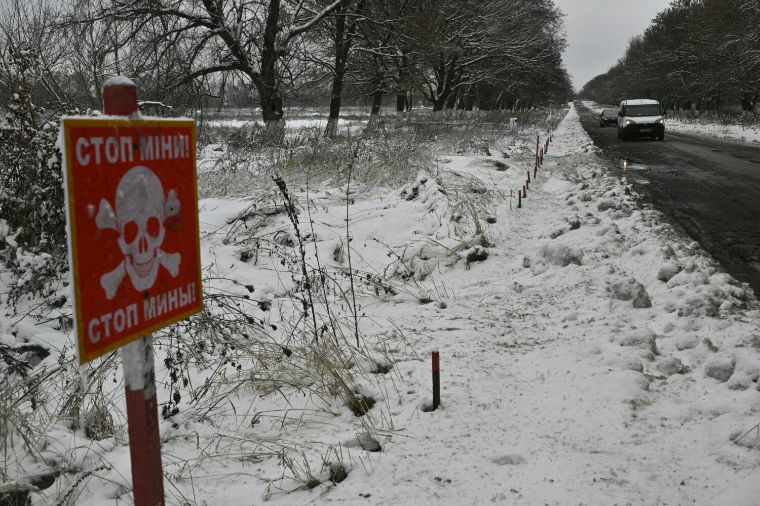 Cars drive past a sign reading Stop-Mines near the village of Makariv west of Kyiv on November 22.2022 amid the Russian Invasion of Ukraine.